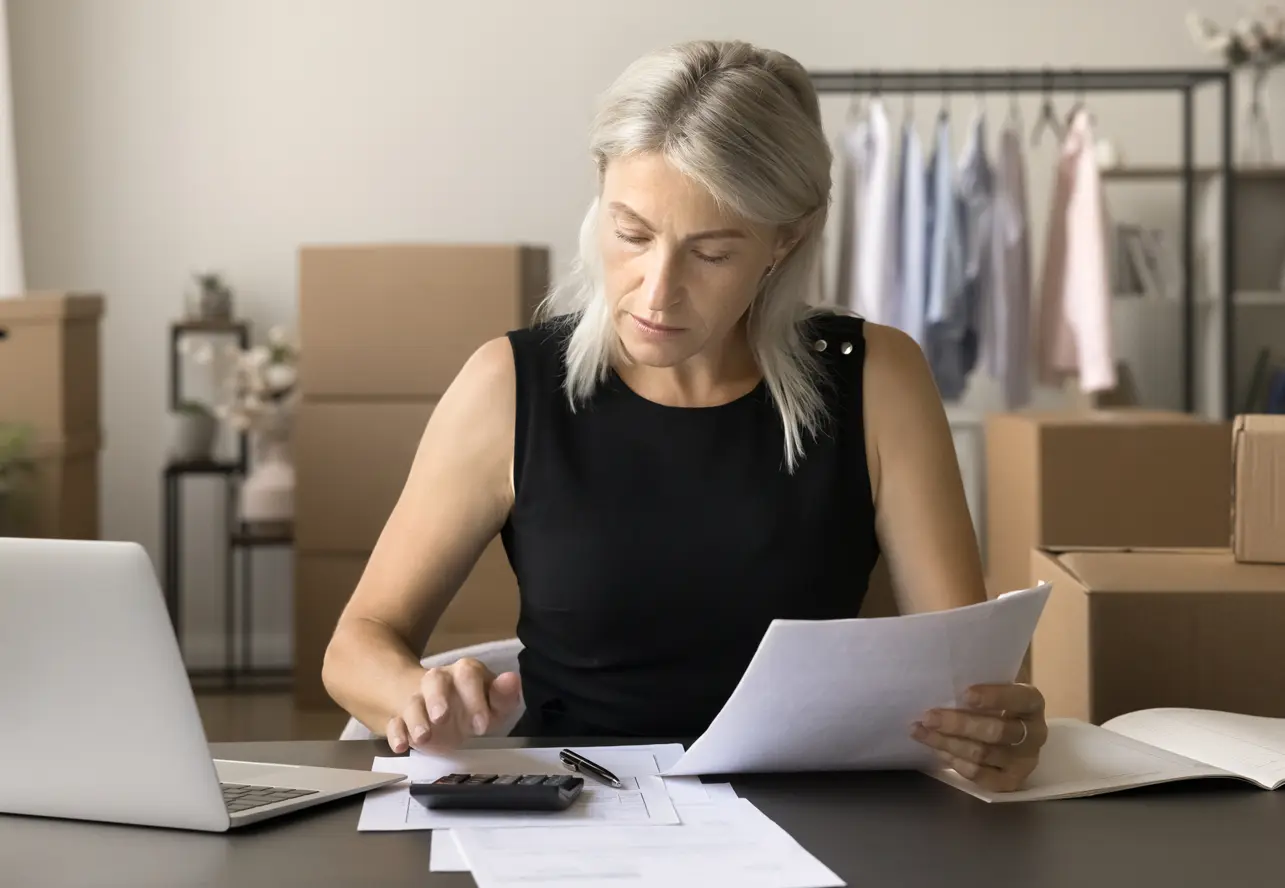 woman business owner checking payroll timesheets with calculator and computer