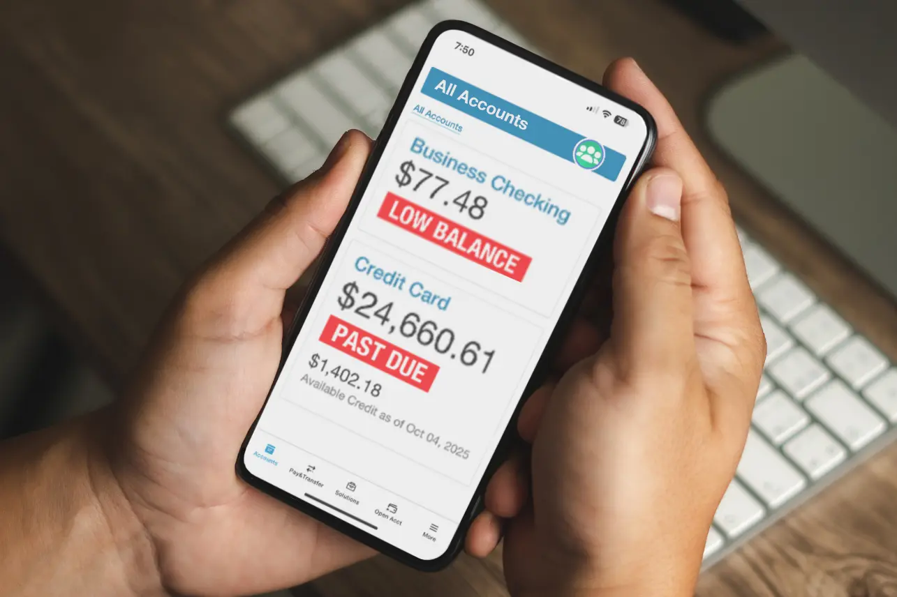 hands holding mobile phone that shows a low balance alert and a past due notice.