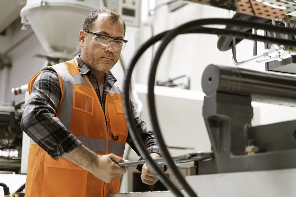 male engineer adjusting machining equipment in a manufacturing plant